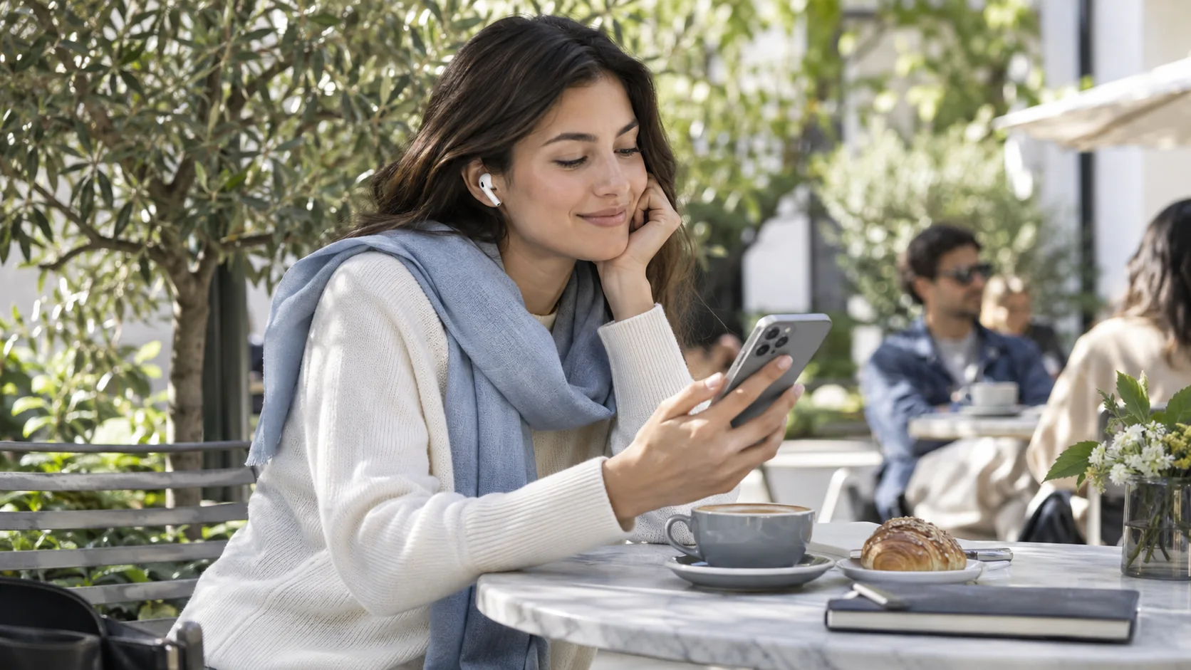 A customer listens with earbuds while using a phone at a cafe.
